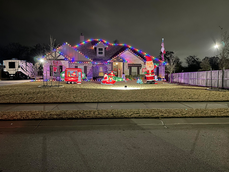 Colorful Christmas light installation in Cedar Park TX. The house has X-Mas lights on the roof and inflated outdoor Christmas decorations in the front yard.