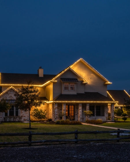 Large brick home in Bryan College station TX with gold Christmas lights on the roof