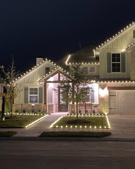 White paneled home in Texas with white lights along the roof
