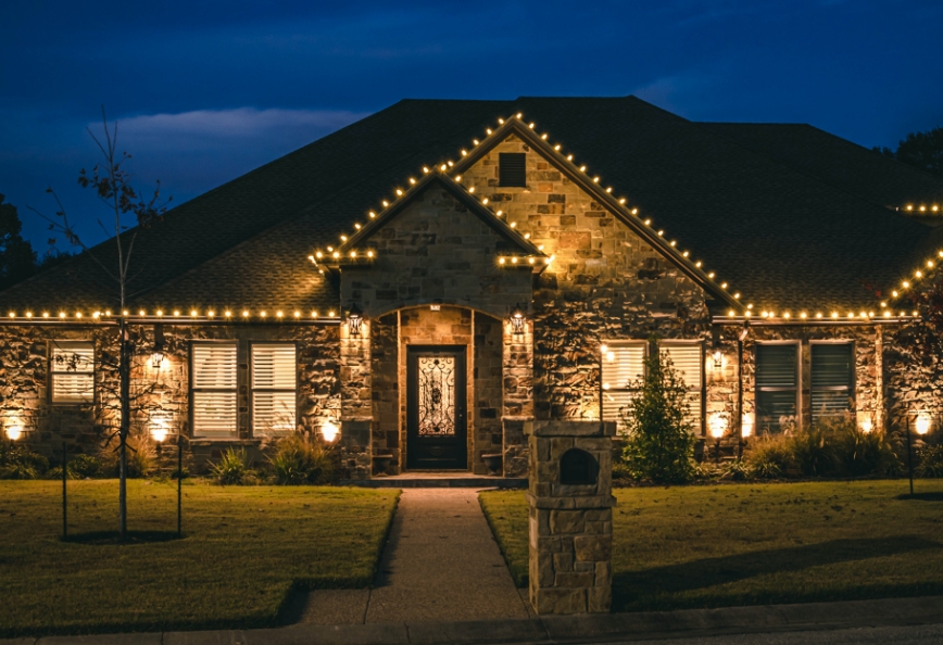 Front of a house with a stone facade. Professional Christmas lights lining the roof.