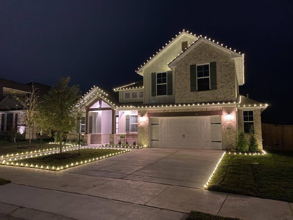 Two-story brick home in College Station with Christmas lights lining the driveway, yard and roof.