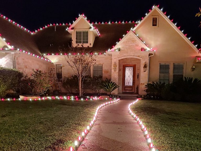 Christmas lights installed lining the front walkway, garden and roof of a house in Cedar Park Texas