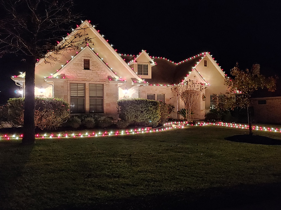 Home in Austin Texas with new Christmas lights. Front garden and roof lined with Christmas lights in alternating colors.
