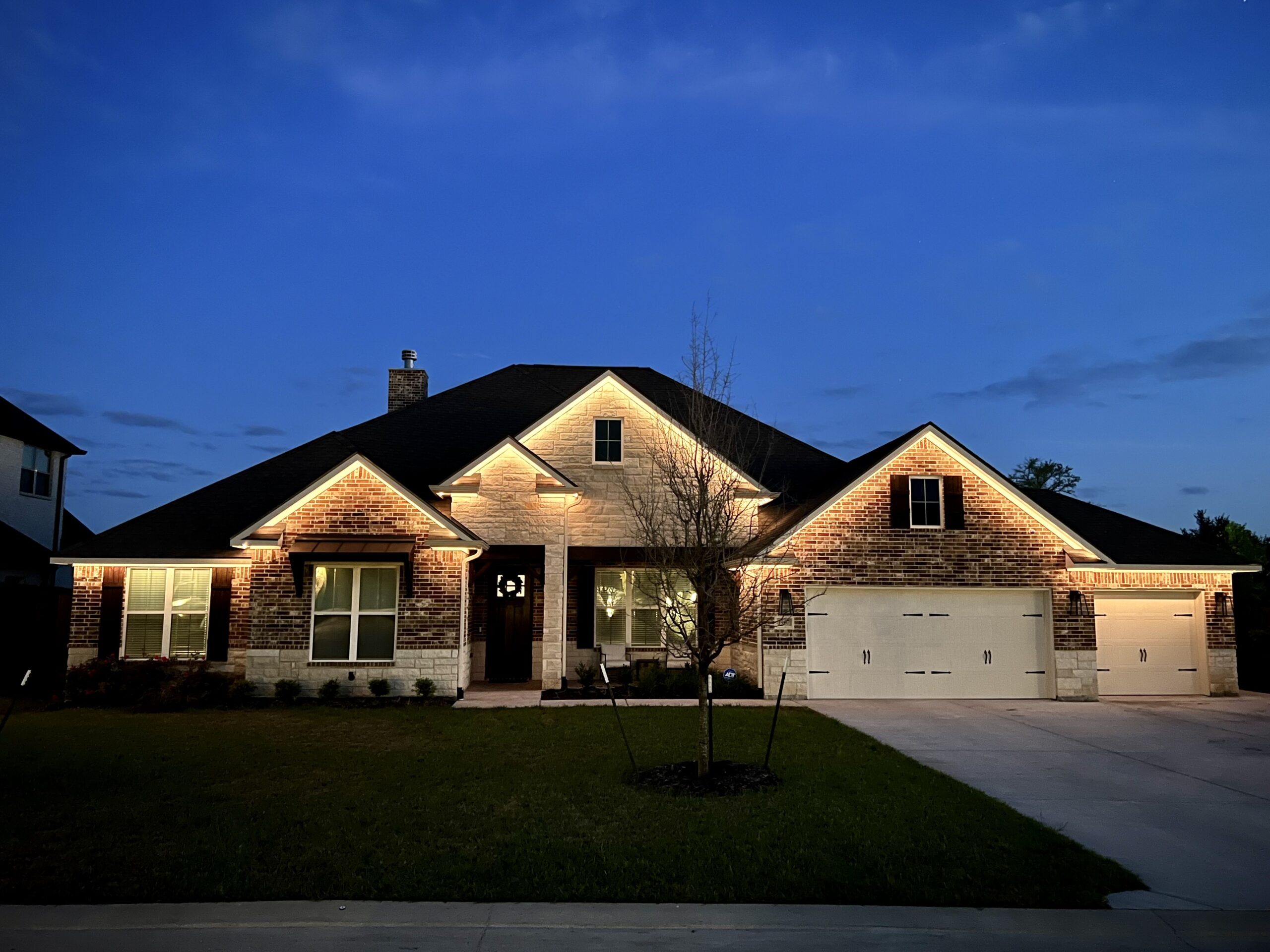 Warm white, permanent lighting installed under the roof line on the front of a house