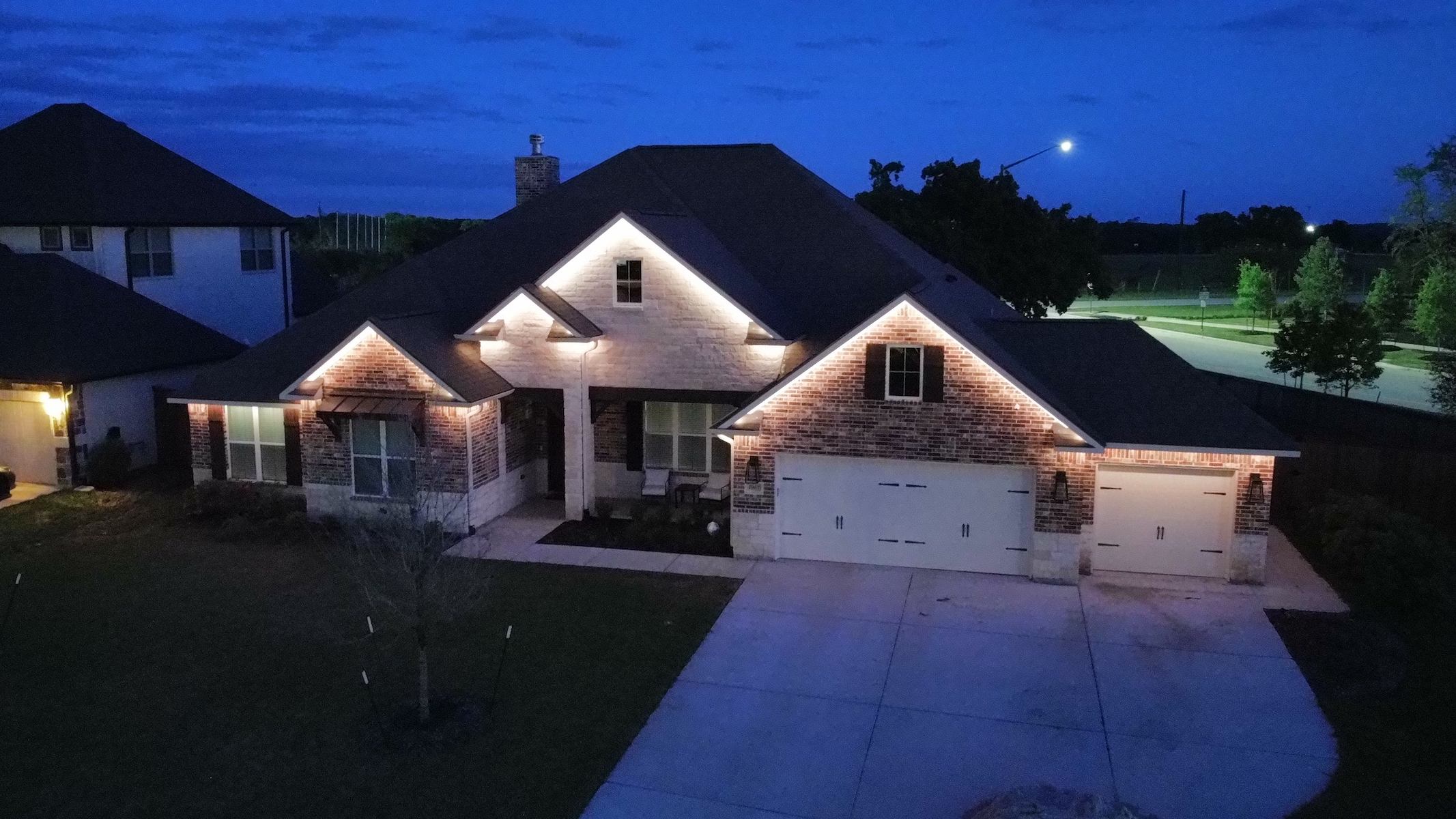 Bright white permanent lighting installed under the roof line on the front of a house