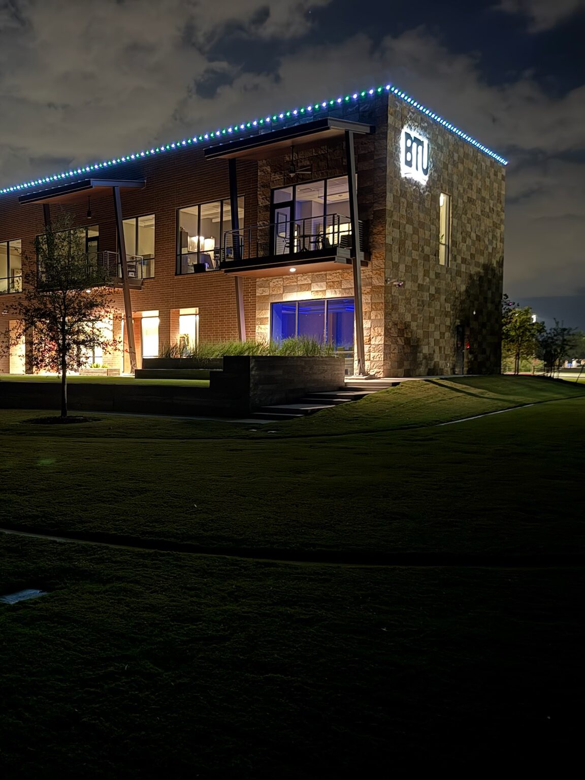 Two-story office building with a roofline outlined in blue and green lights