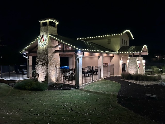 Neighborhood amenity center and pool house outlined in warm white Christmas lights with a lighted wreath